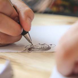 A person drawing on a piece of paper

AI-generated content may be incorrect.